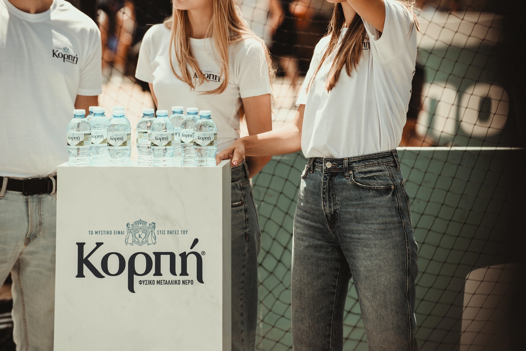 Το κιούσκι με νερά Κορπή και άνθρωποι φορούν μπλούζες με το λόγκο Κορπή
