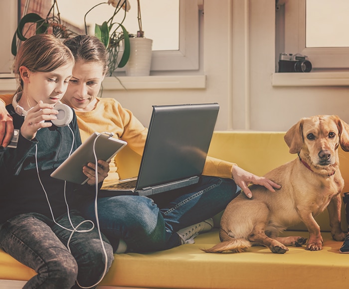 Mom child and dog sitting on their couch with laptop